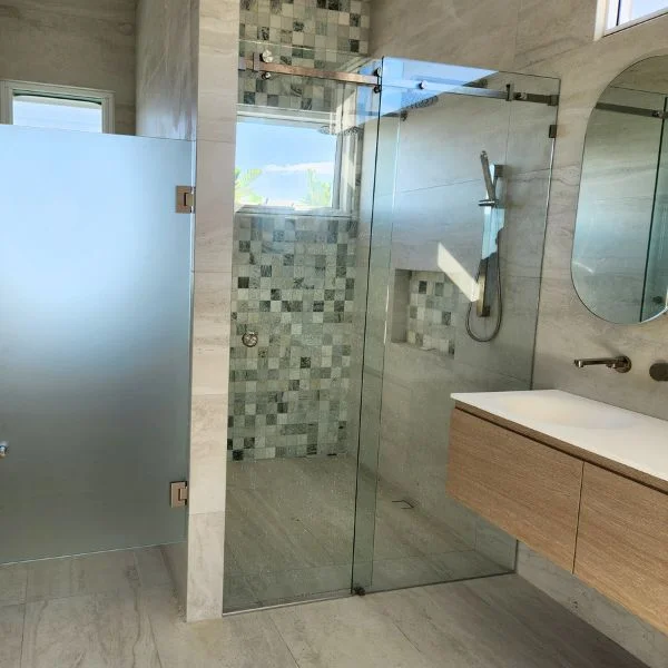 Two showers installed one frameless sliding shower screen on the right and one wall to wall frosted glass on the left.