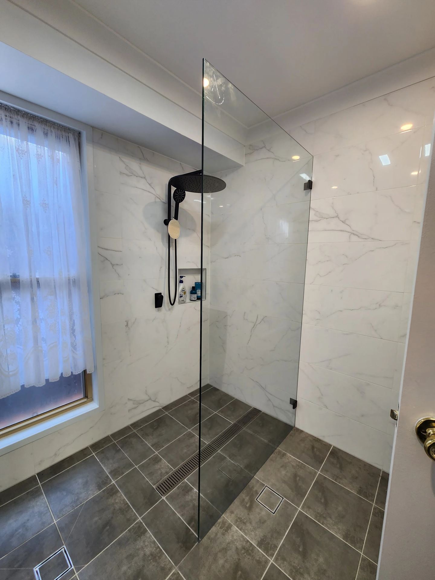 frameless shower screen with black hardware installed in Concord West by Showerland