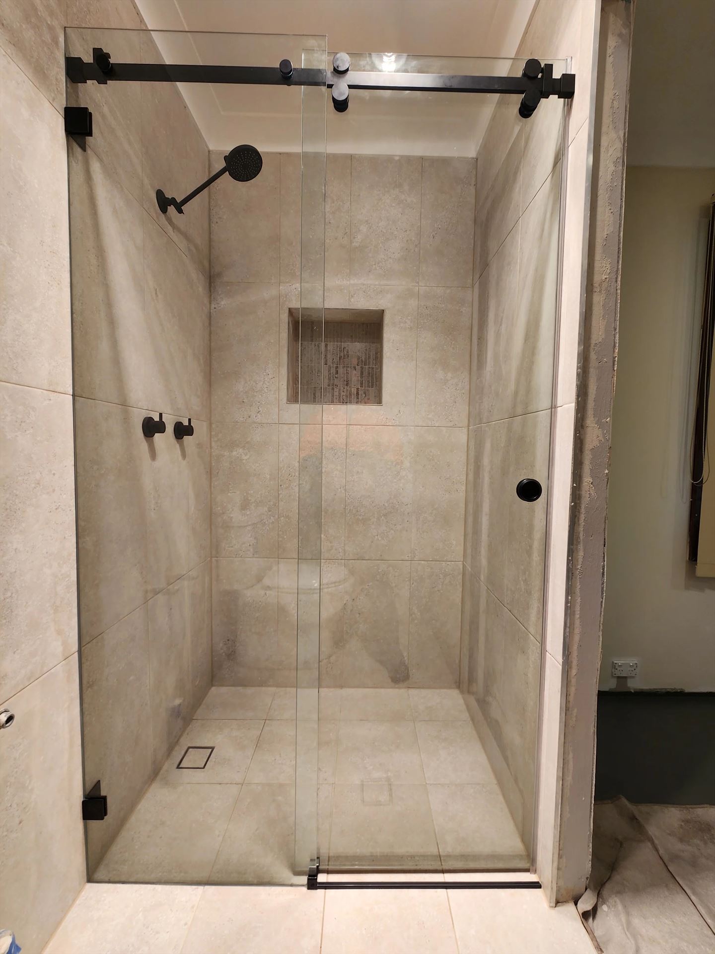Frameless sliding shower door on a matt black bar and rollers in Ingleburn