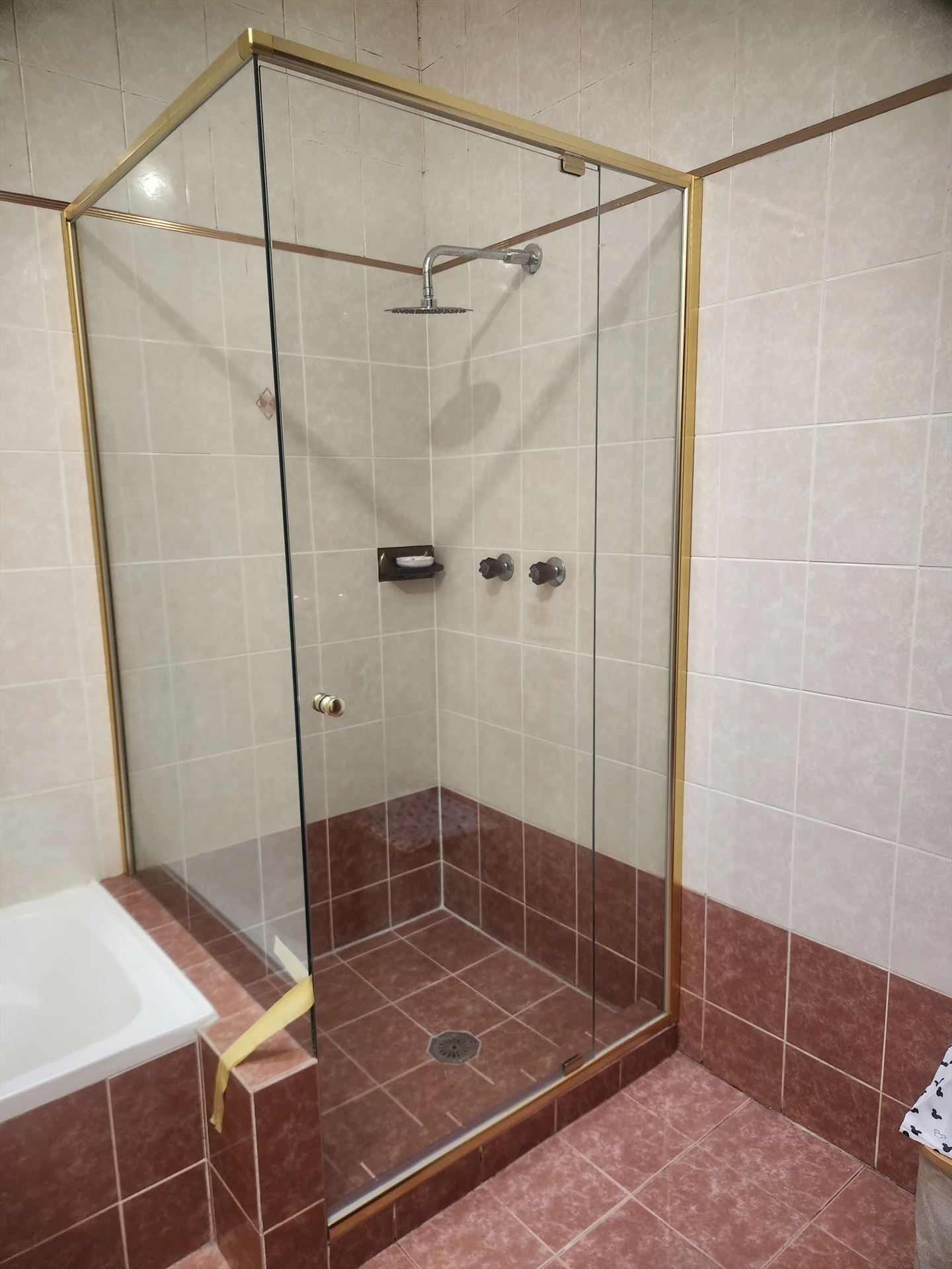 semi shower screen with gold hardware installed in West Ryde by Showerland