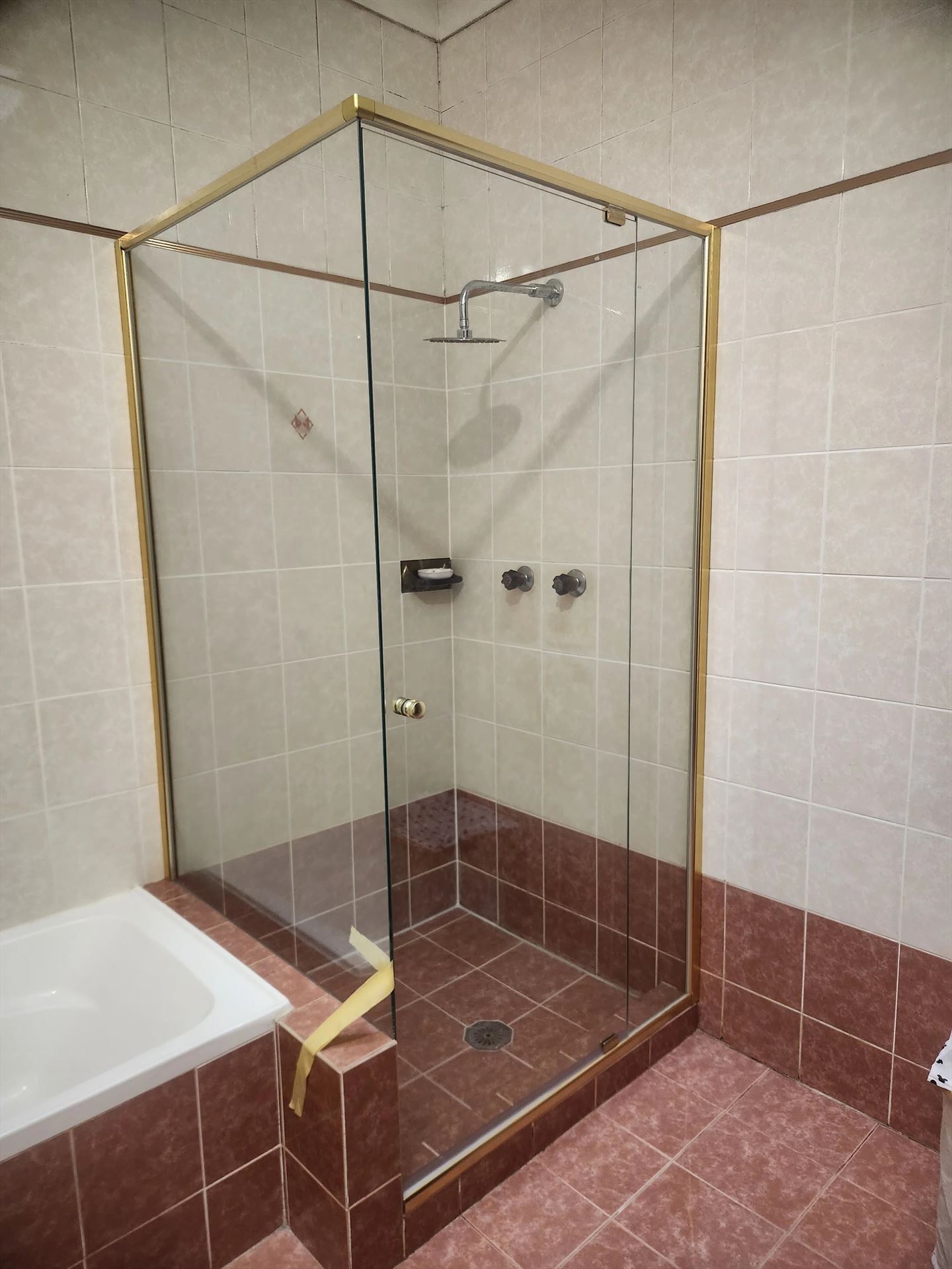 semi shower screen with gold hardware installed in West Ryde by Showerland