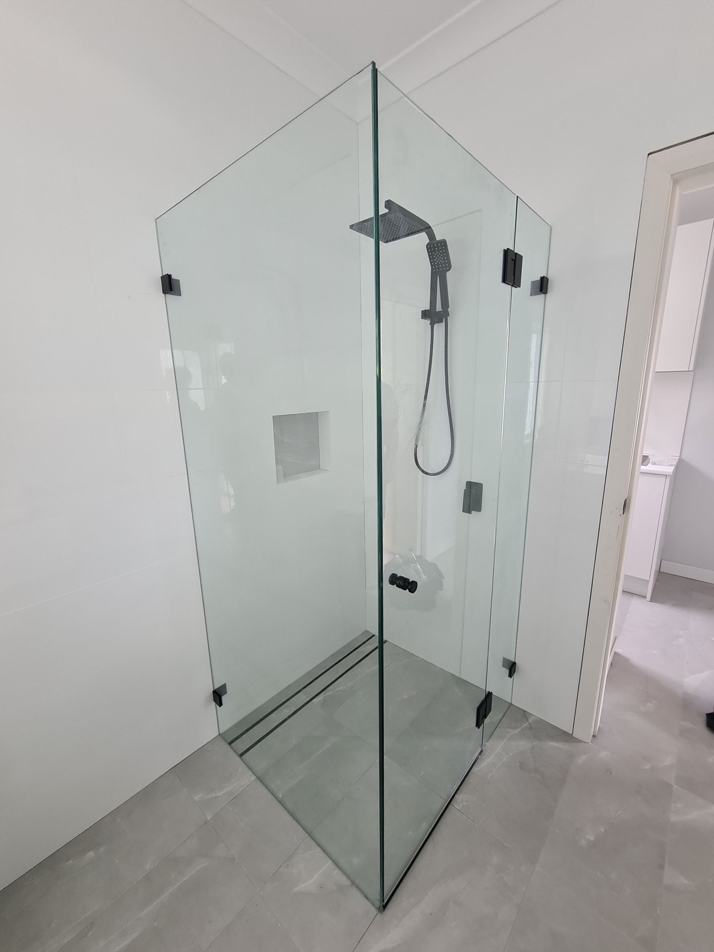 frameless shower screen with black hardware installed in Loftus by Showerland