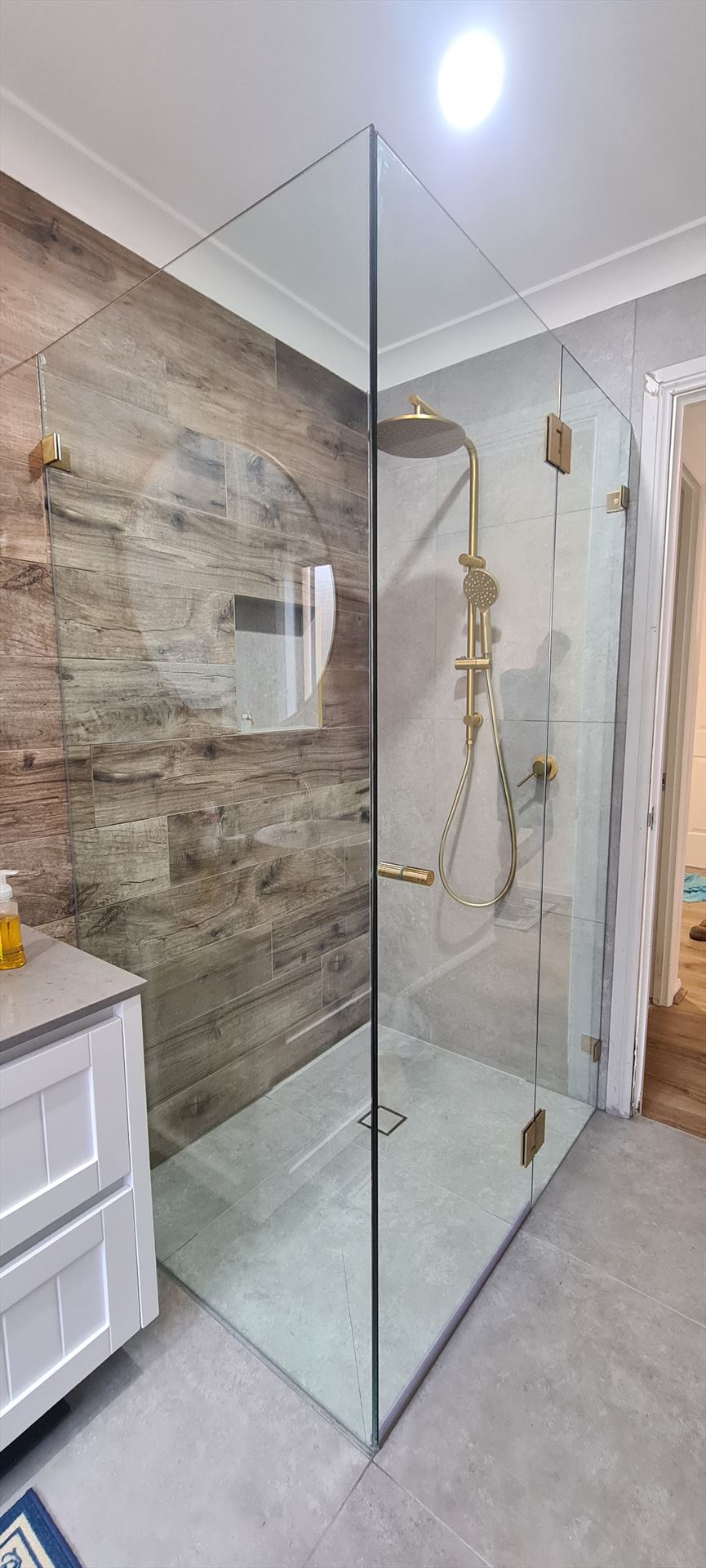 frameless shower screen with gold hardware installed in Acacia Gardens by Showerland