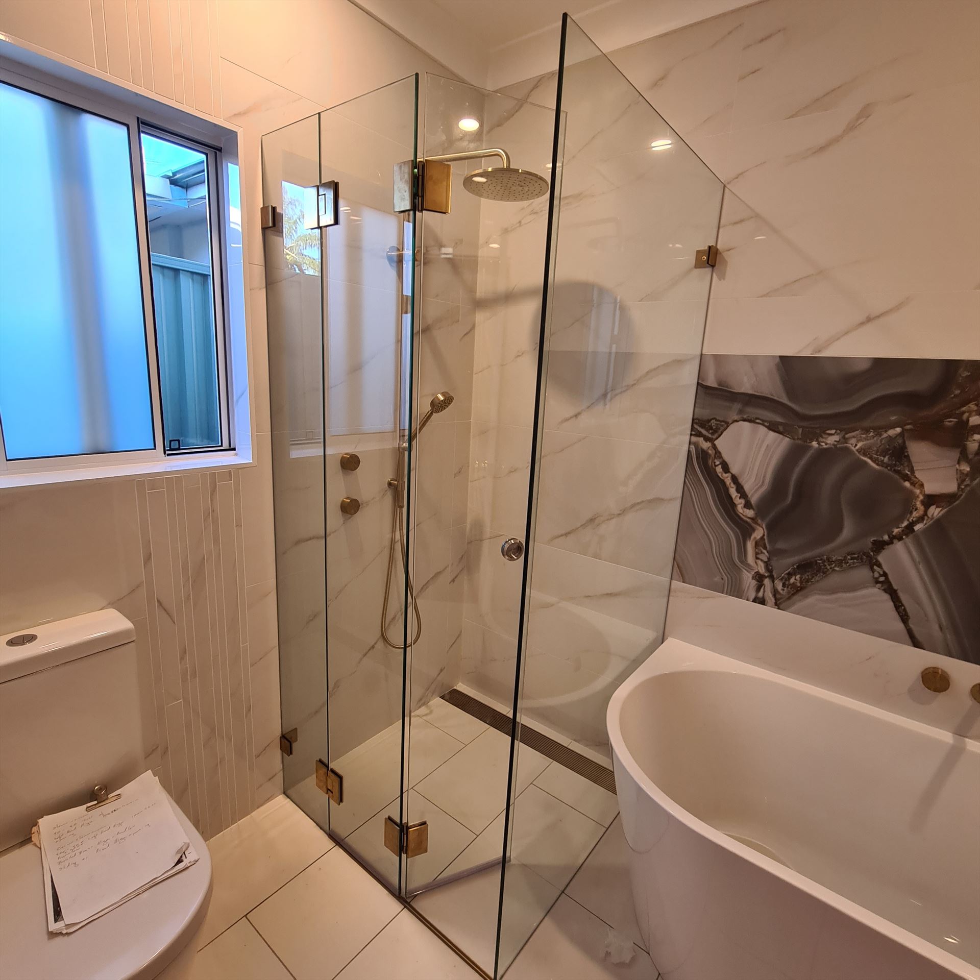 frameless shower screen with brass hardware installed in Riverwood by Showerland