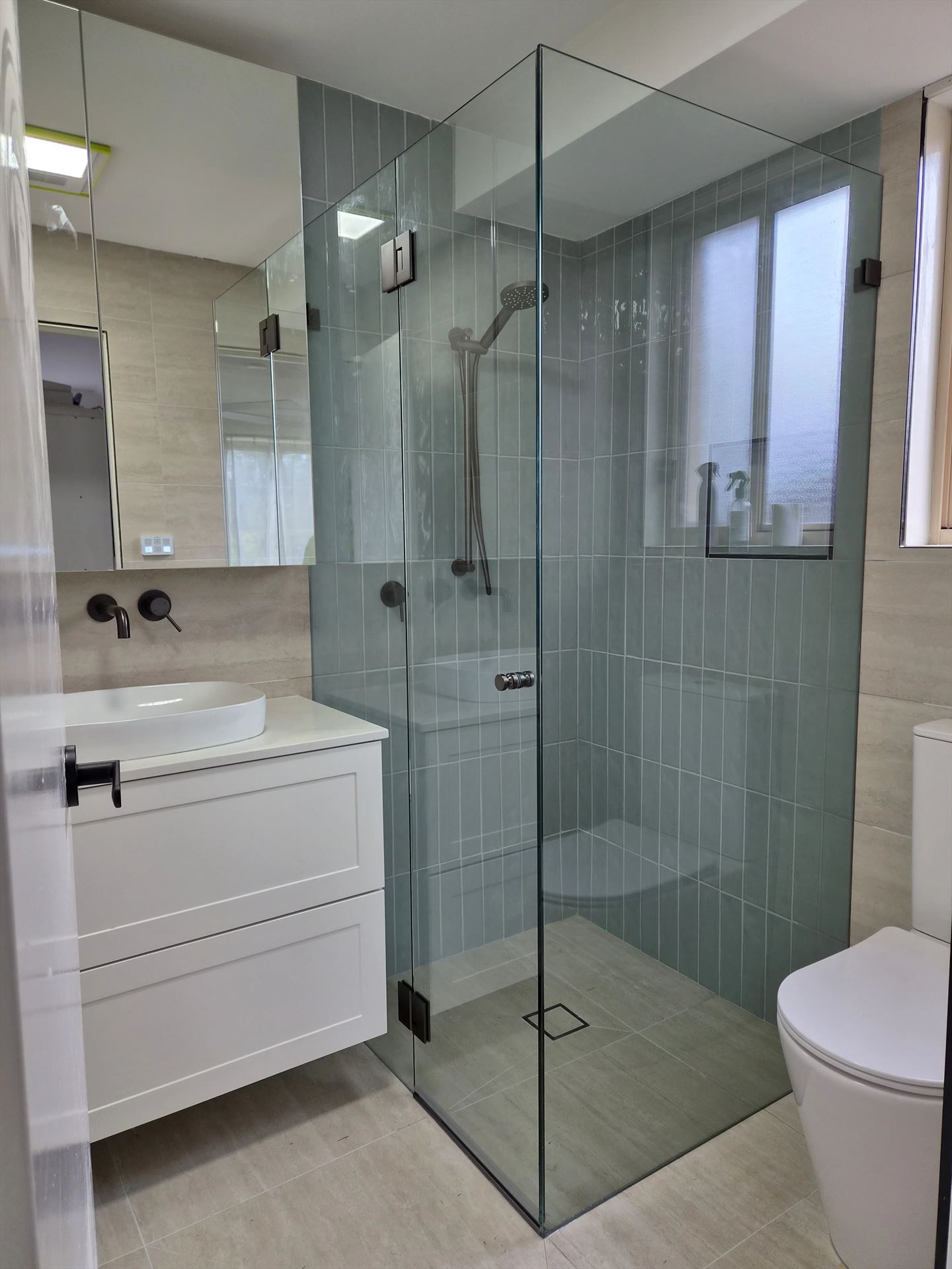 frameless shower screen with black hardware installed in Warriewood by Showerland