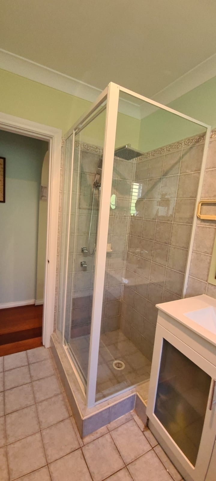 Custom fully framed white pivot shower screen built to the tile height, Sydney