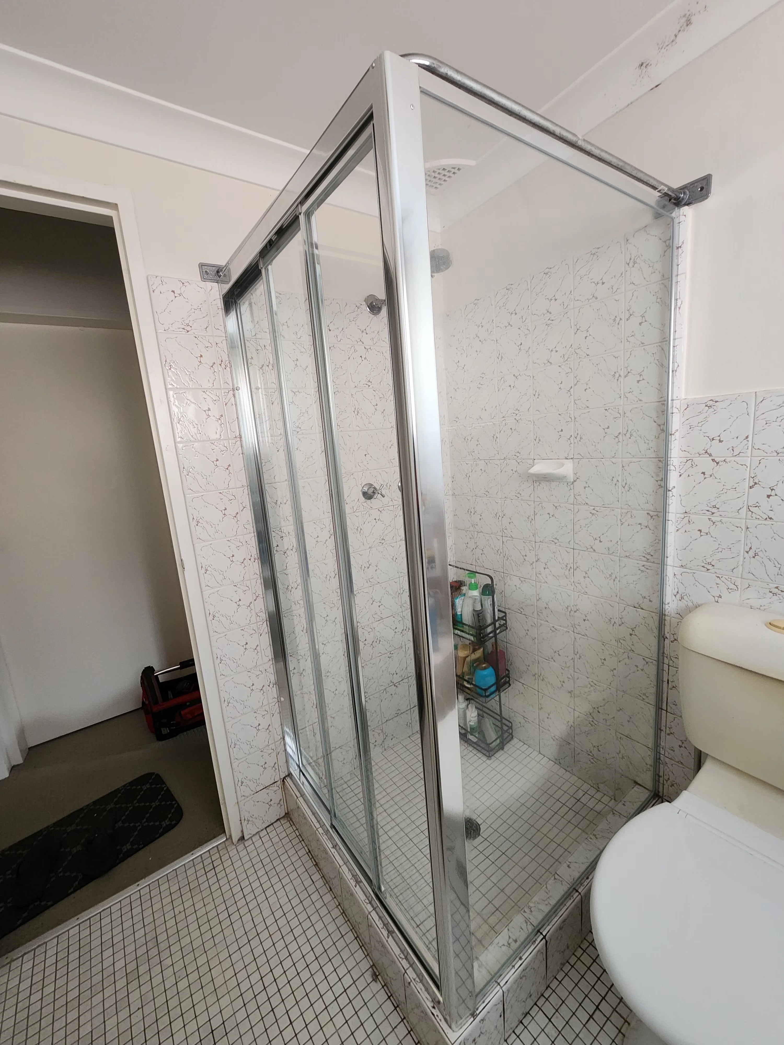 Custom shower screen sitting on a tiled hob with chrome sliding door, Sydney