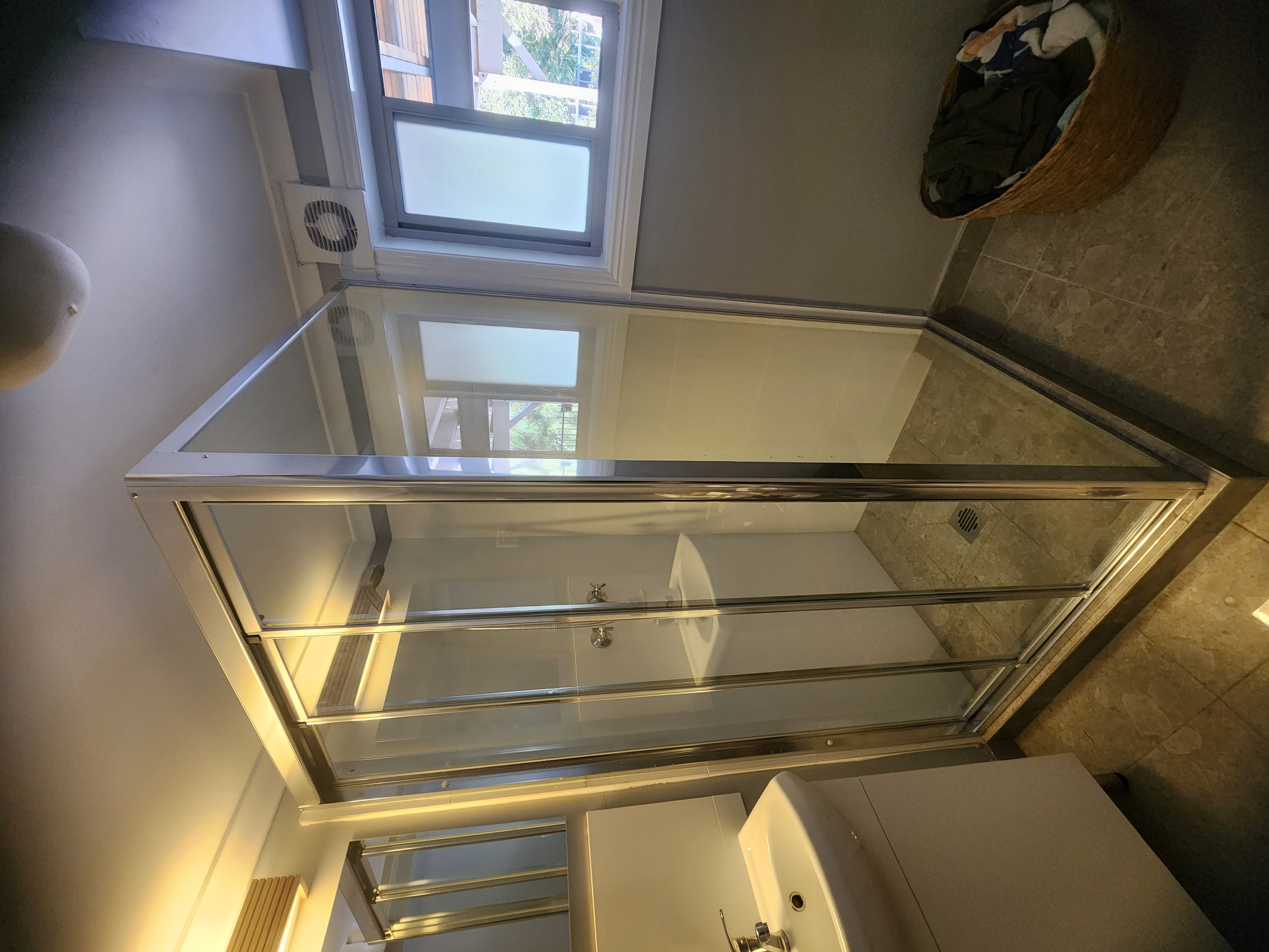 Custom shower screen cut around a tiled hob step, chrome sliding door, Sydney