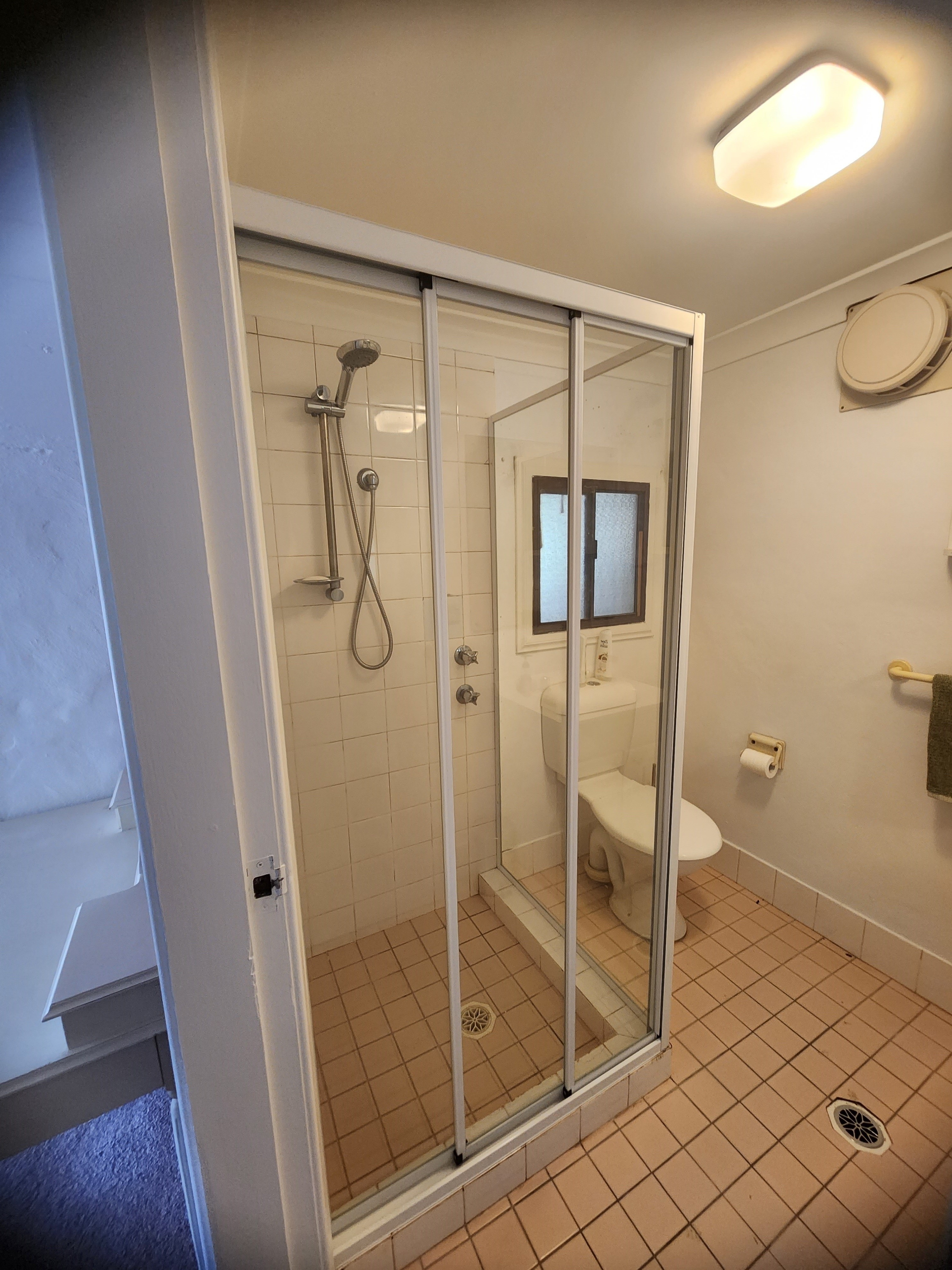 Custom shower screen glass cut to follow stepped wall tiles in a Sydney bathroom