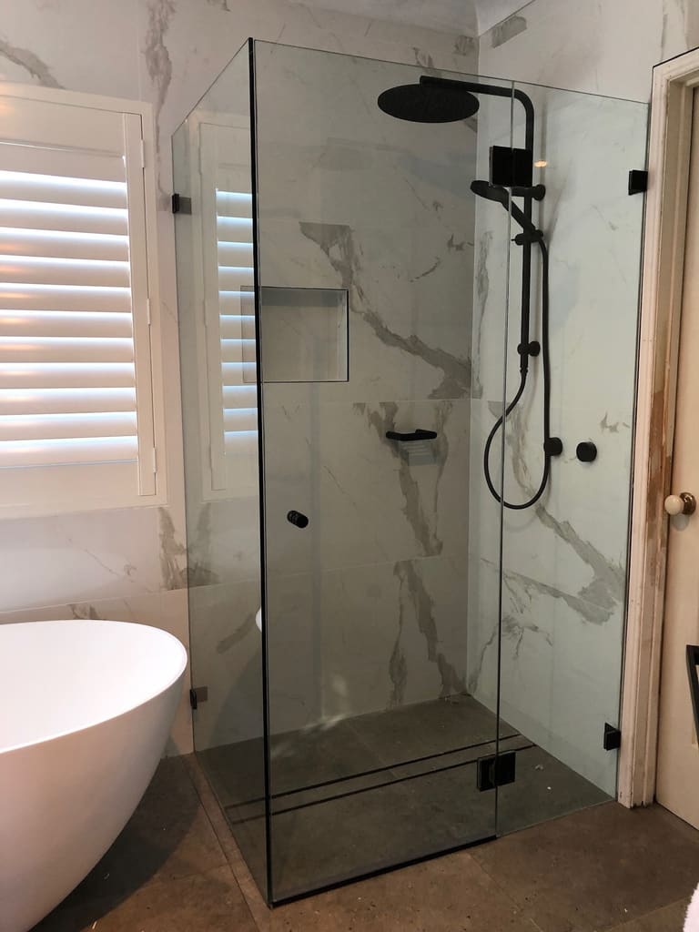 Premium frameless shower screen with marble tiles and matte black fittings