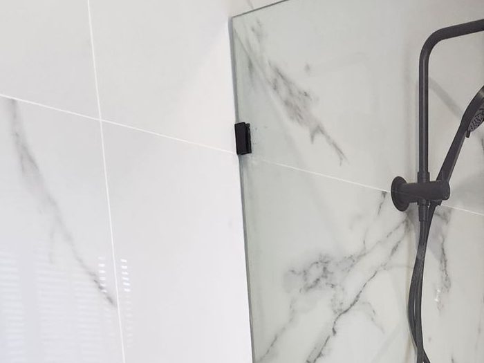 Close view of a bracket holding a frameless fixed panel in Bankstown